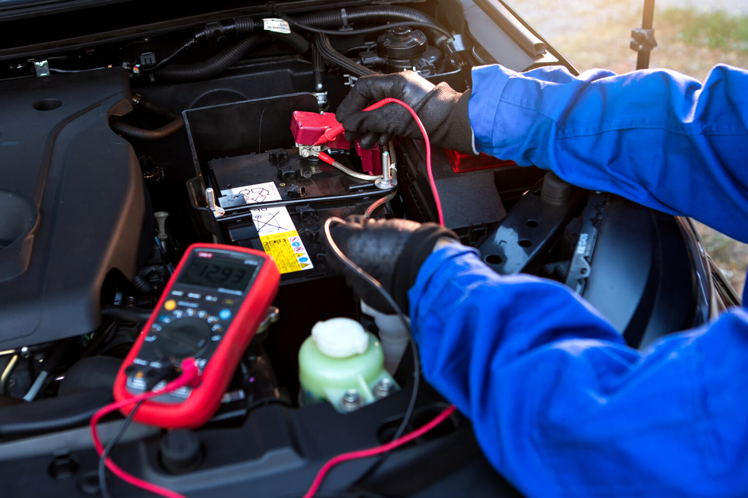 Technician carrying out an electrical check under the bonnet of a vehicle